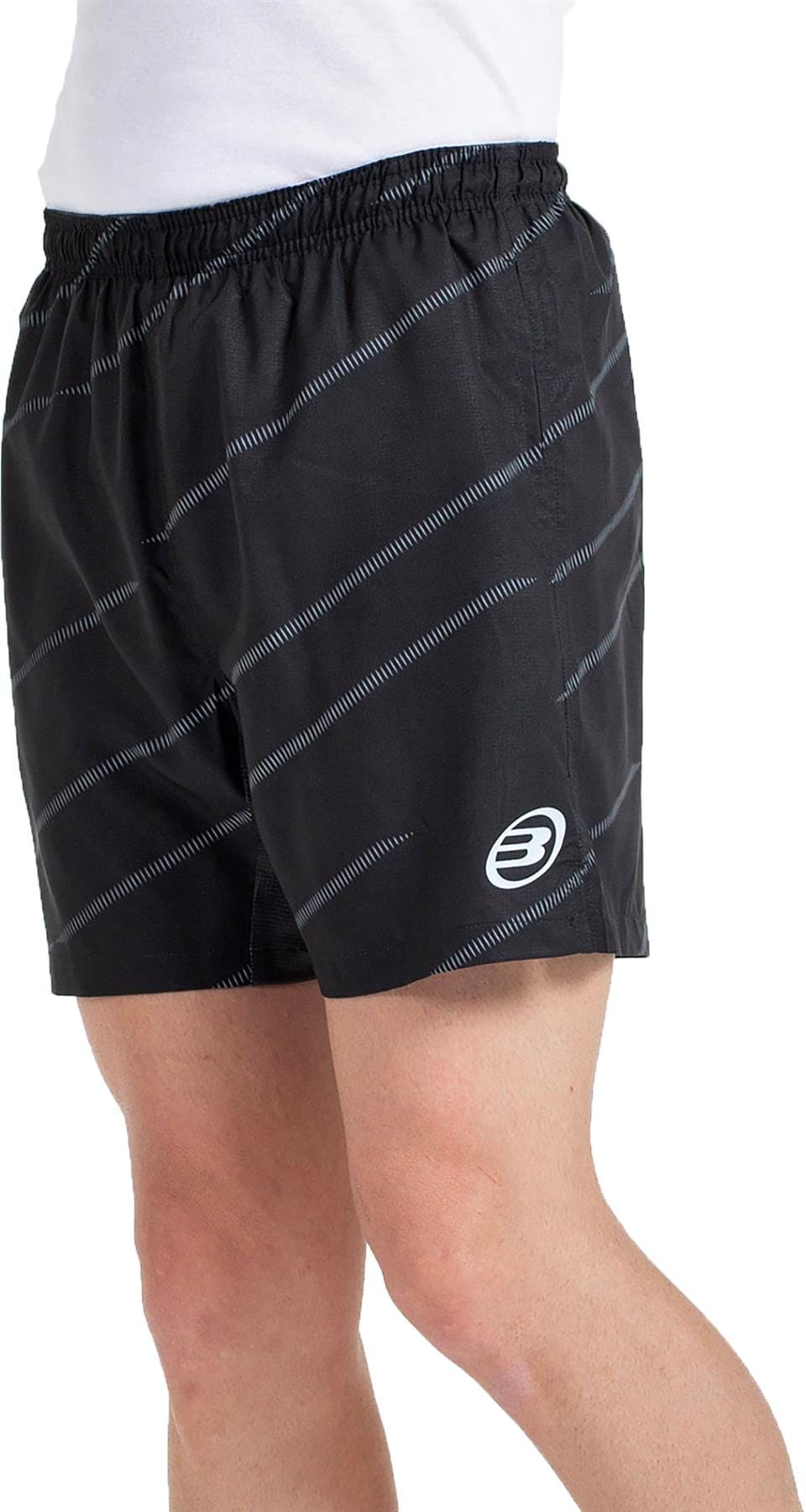 A person in Bullpadel Cabanas Men's Padel Shorts – Black, featuring thin diagonal white stripes, Quickerdry tech, and a white left-leg logo by Bullpadel, paired with a white shirt against a white background.