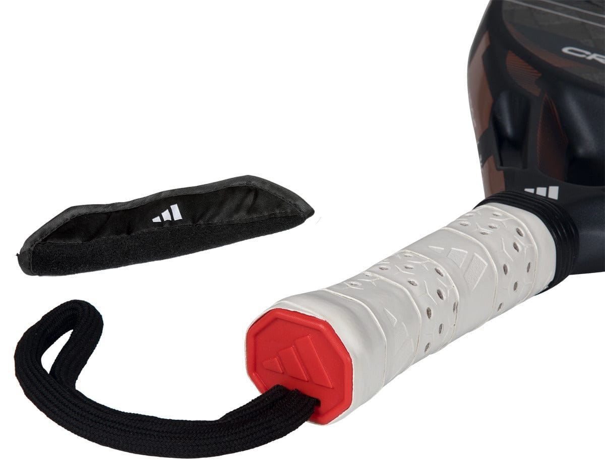 Close-up of the adidas Cross It Ctrl 2026 Padel Racket - Black, featuring a white perforated grip, wrist strap, detached black cover, carbon fibre construction, and Spin Blade Mould tech on a white background.