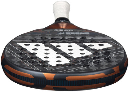 Close-up of the ADIDAS Cross It Ctrl 2026 Padel Racket – Black by adidas, featuring a black and orange design, Spin Blade Mould technology on the perforated hitting surface, and a white grip handle.