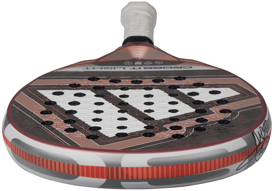 A close-up of the adidas Cross It Light 2026 Padel Racket – White / Pink, featuring a carbon fibre frame, white grip, patterned face with circular holes, and a bold pink and white geometric design.