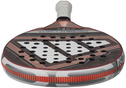 A close-up of the adidas Cross It Light 2026 Padel Racket – White / Pink, featuring a carbon fibre frame, white grip, patterned face with circular holes, and a bold pink and white geometric design.