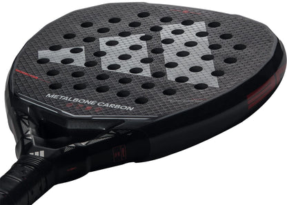 Close-up of the adidas Metalbone Carbon 2026 padel racket for advanced players, featuring a textured round surface and multiple holes. "METALBONE CARBON" appears on the face of this high-performance adidas racket.
