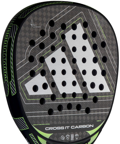 Close-up of the adidas Cross It Carbon 2026 Padel Racket - Black / Green, an advanced-level carbon fibre racket featuring a large white geometric logo, circular perforations, green accents, and "CROSS IT CARBON" at the bottom of the face.