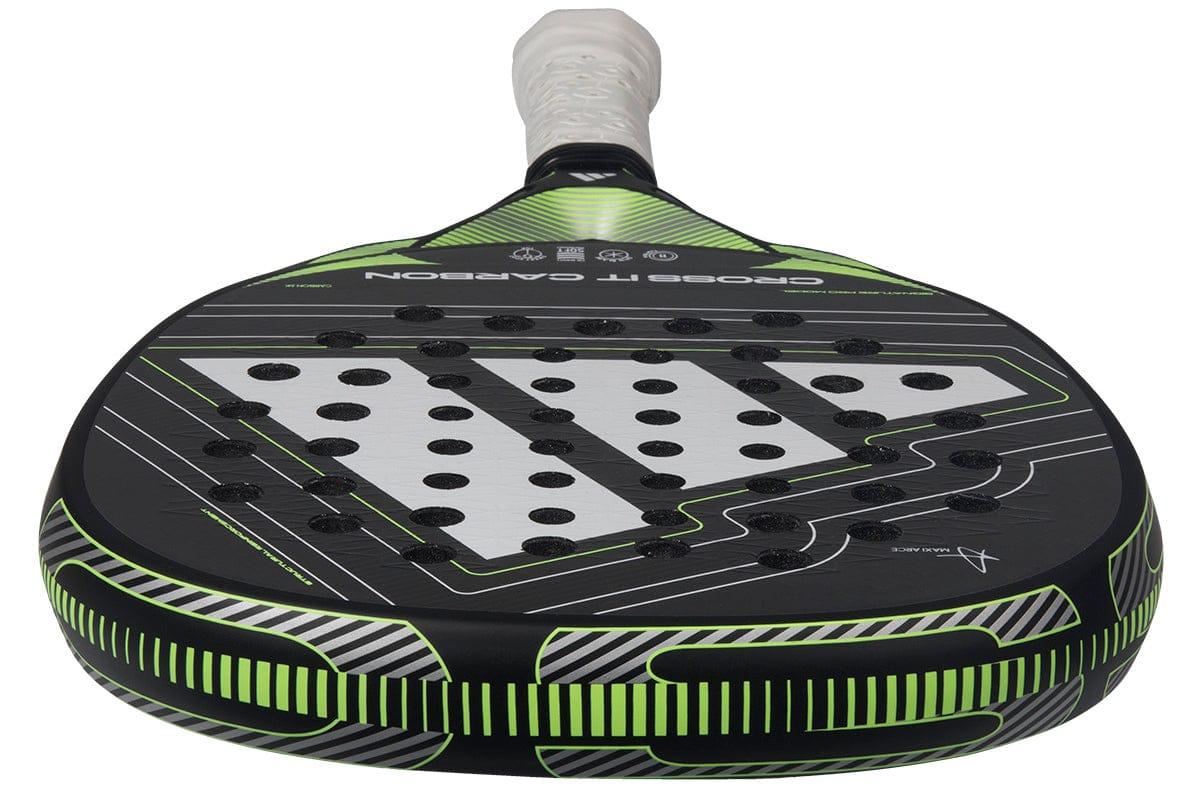 A close-up of the adidas Cross It Carbon 2026 Padel Racket in black and green, featuring a carbon fibre face with multiple round holes and a white grip.