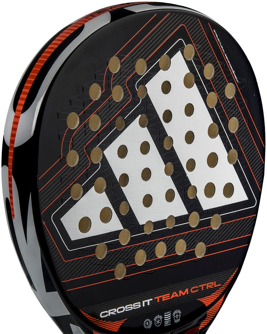 A close-up of the adidas Cross It Team Ctrl 2026 Padel Racket in black and orange, displaying the white adidas logo, multiple round holes on the face, and "CROSS IT TEAM CTRL" text near the base.