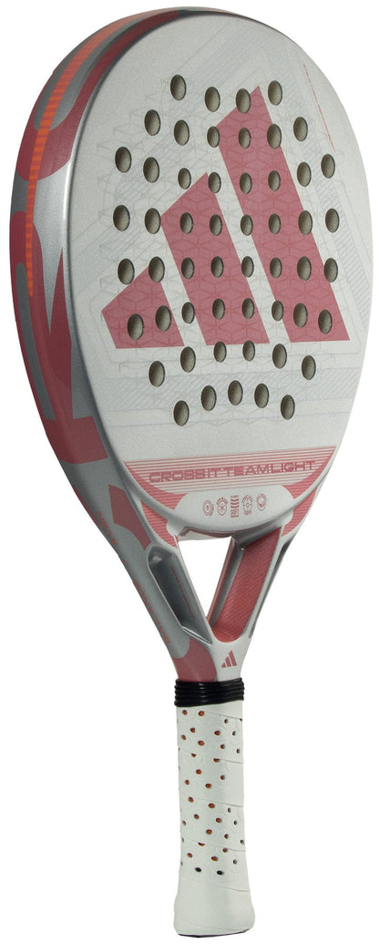 A white and pink adidas Cross It Team Light 2026 Padel Racket features a perforated surface, geometric design, Extra Power Grip, and "CROSS IT TEAM LIGHT" printed on the lower part of the lightweight racket face.