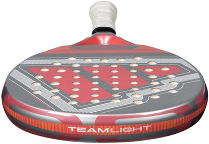 A close-up of the lightweight adidas Cross It Team Light 2026 Padel Racket in white and pink, showing "TEAM LIGHT" on the edge, Extra Power Grip, and multiple circular holes on its face.