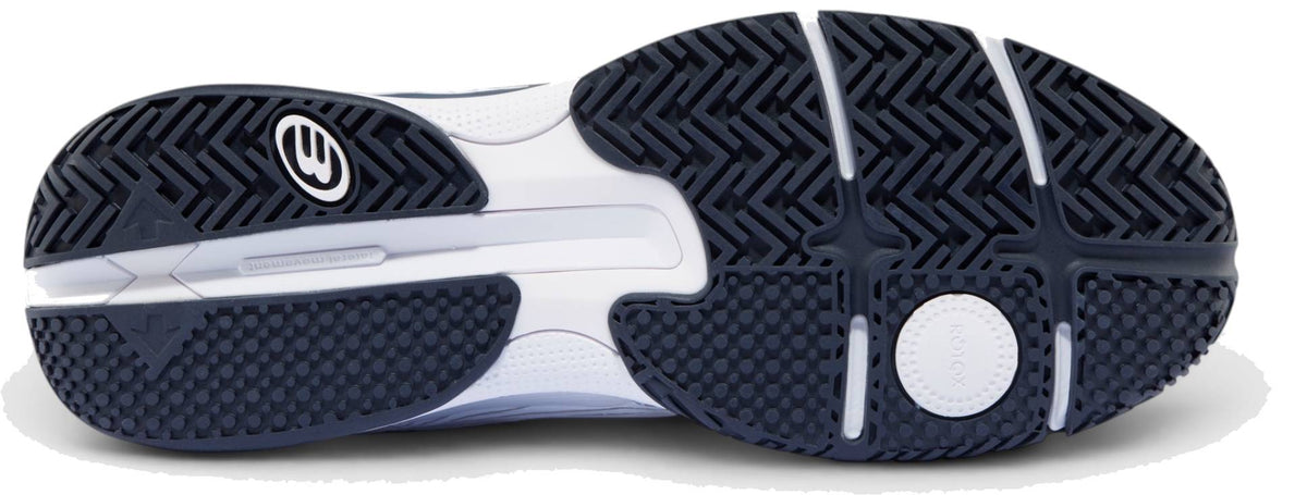The image shows the black and white textured sole of the Bullpadel Hybrid Fly 26I Mens Padel Shoes - White / Navy, featuring a hybrid outsole tread and a stylized FASTLAB logo near the heel.
