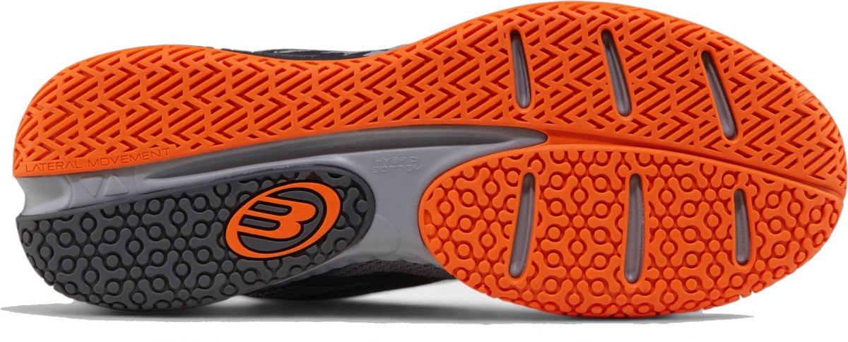 Close-up of the Bullpadel Ionic 26I Mens Padel Shoes - Dark Grey sole with orange and gray tread, circular logo, and traction grooves—perfect for intermediate and advanced players.
