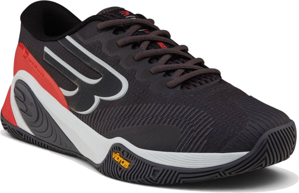 The Bullpadel Vertex Vibram 26I Mens Padel Shoes - Asphalt feature a black, red, and white design with a textured Vibram outsole and bold side logo, displayed at an angle on a white background.