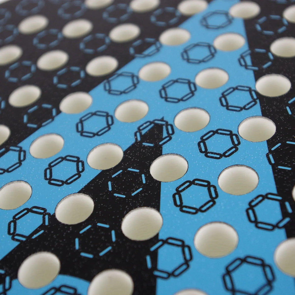 Close-up of the Karakal Chaos Dynamic 2026 Padel Racket, featuring a 12K carbon graphite surface with a pattern of circular holes over a black and blue graphic design.