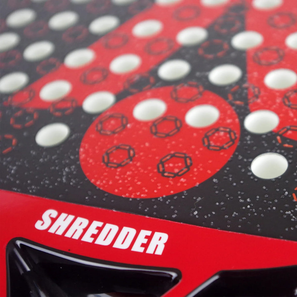 Close-up of a Karakal Chaos Shredder 2026 padel racket face with a red and black geometric pattern, rows of white circular holes, and the word “SHREDDER” printed in white near the base.