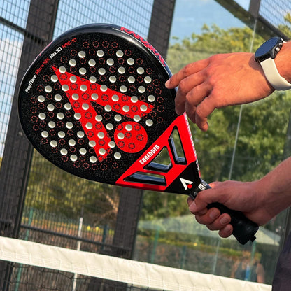 A person holds a black and red Karakal Chaos Shredder 2026 padel racket, featuring a triangular logo and multiple circular holes on the face.