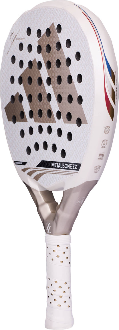 White and grey ADIDAS Metalbone ZZ Carbon Zinedine Zidane 2026 padel racket featuring a perforated surface, gold-toned logo, and a white grip handle.