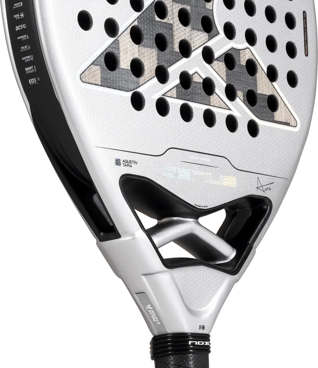 Silver and black NOX AT10 Genius 12K Alum Xtrem By Agustín Tapia 2027 padel racket with a perforated hitting surface, showing the signature of Agustín Tapia and technical feature labels printed on the frame.