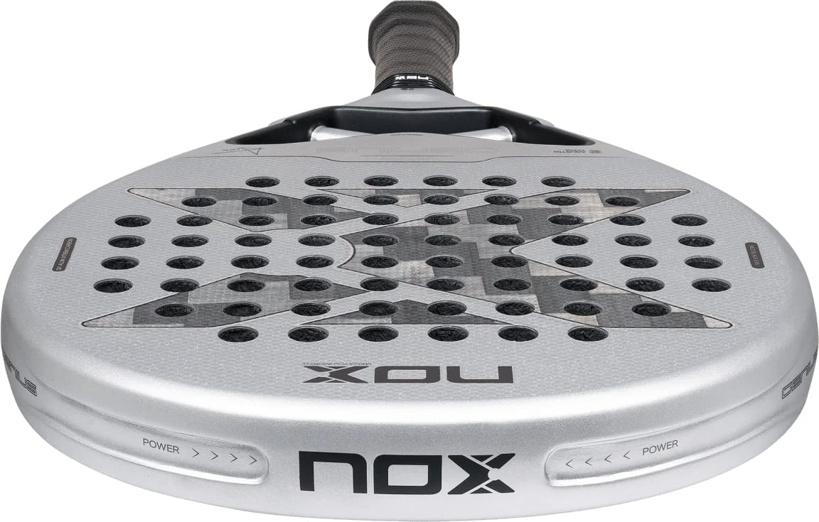 A silver and black NOX AT10 Genius 12K Alum Xtrem By Agustín Tapia 2027 padel racket with a teardrop shape, a perforated face, and a centered x-pattern.