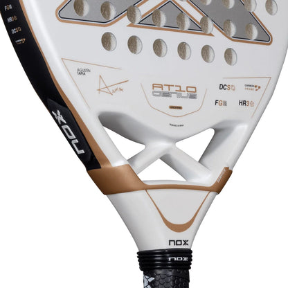 White NOX AT10 Genius Junior 2026 padel racket with a perforated face, copper-colored accents, and technical branding text.