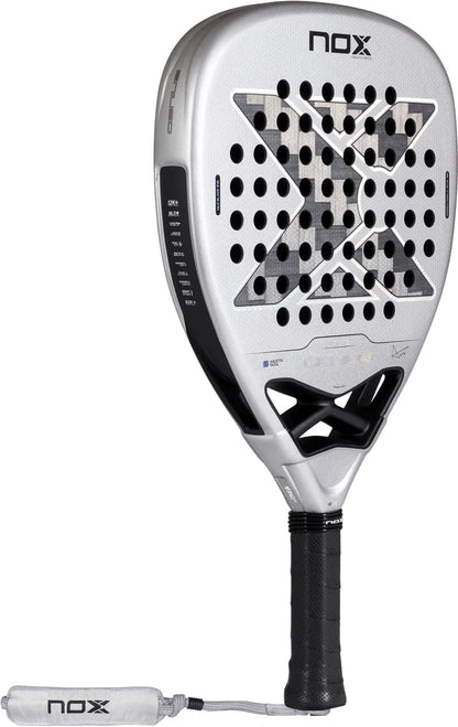A silver and black NOX AT10 Genius Attack 12K Alum Xtrem By Agustín Tapia 2027 padel racket featuring a perforated head, an X-shaped pattern, and a wrist strap.