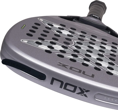 Close-up of a grey NOX AT10 Genius Attack 18K Alum By Agustín Tapia 2027 padel racket featuring a textured face, a perforated surface, and a removable weight balancer attached to the frame.