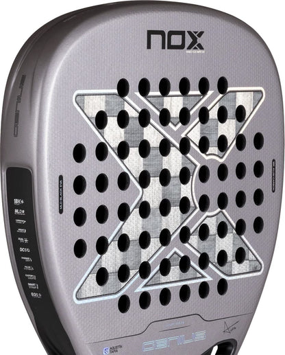 Grey NOX AT10 Genius Attack 18K Alum By Agustín Tapia 2027 Padel Racket with a diamond-shaped grid of holes, a large X pattern in the center, and technical specification text along the side.
