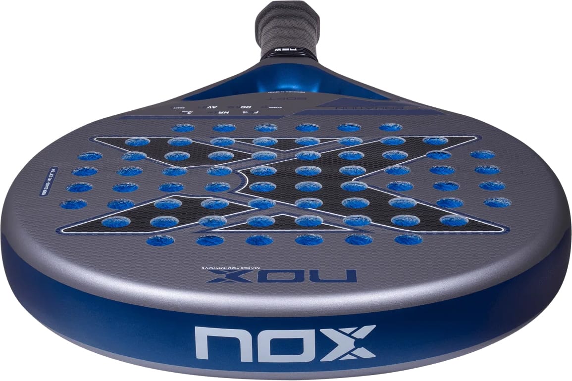 A round NOX Equation Soft Advanced 2027 padel racket featuring a dark gray surface, blue perforated holes in an X pattern, and a blue handle.
