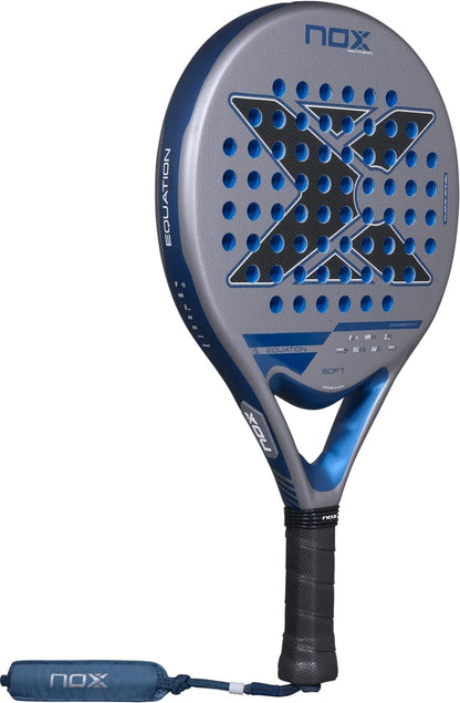 A gray and blue NOX Equation Soft Advanced 2027 padel racket with a perforated face, featuring a large black X logo and a wrist strap attached to the handle.