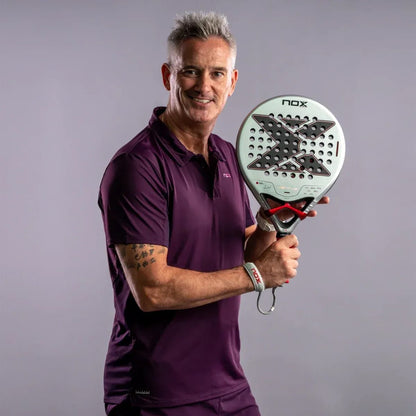 A man in a purple polo shirt smiles while holding a round, light-colored NOX Ventus Control 3K By Miguel Lamperti 2027 padel racket.