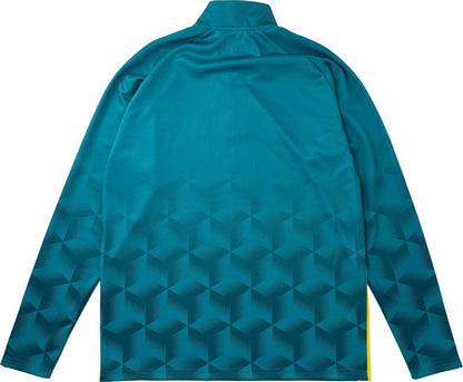 The Yonex YML7 Unisex Padel Midlayer in teal is displayed from the back, highlighting its bold geometric cube pattern that intensifies toward the hem. This long-sleeve athletic jacket from Yonex features a short collar with a discreet quarter zip and small yellow accents near the sides at the bottom.