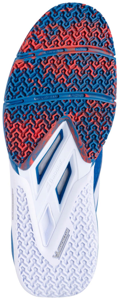 The image displays the bottom view of the Babolat Movea 2 Men's Padel Shoes in Seaport/Cherry Tomato, featuring a brand-signature textured sole with red and blue zigzag patterns at the forefoot and white geometric designs at the heel and midfoot.