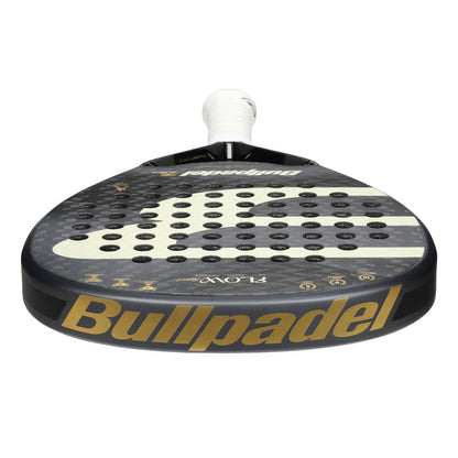 A close-up of the Bullpadel Flow Legend 2026 Padel Racket in black, featuring a gold-accented perforated surface and white handle, inspired by Alejandra Salazar.