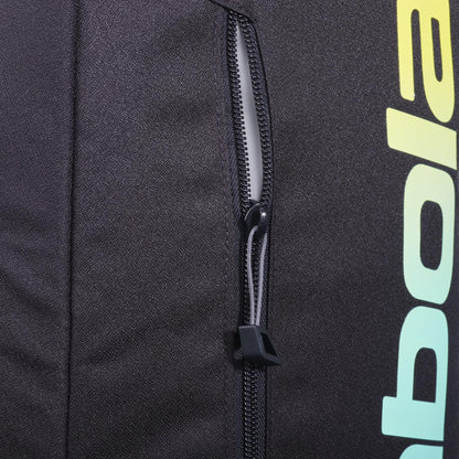 Close-up of the black zippered pocket on the Babolat Court Lite Padel Backpack - Black / Multi, showing part of the "Babolat" logo in a yellow-green gradient and a peek at the dedicated racket compartment on the right.
