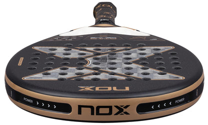 Close-up of the NOX AT10 Genius 18K Alum By Agustín Tapia 2026 Padel Racket in black and gold by NOX, featuring a Dual Spin surface, large "X" design, multiple holes, and "POWER" printed on the edge near the handle.