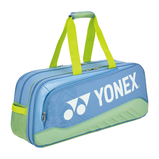 The Yonex 02531WEX Expert Tournament Padel Bag in Smoke Blue, ideal for expert padel players, showcases a standout design with yellow-green straps. Featuring the Yonex logo and multiple zippers, this high-quality bag is perfect for carrying sports equipment effortlessly.