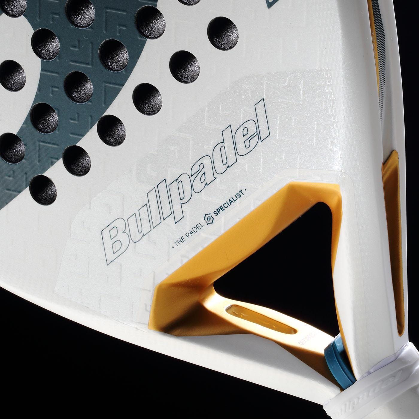 Close-up of the lightweight Bullpadel Pearl 2026 Padel Racket - White, featuring a gold accent, textured surface for injury prevention, and the Bullpadel logo on the frame against a black background.