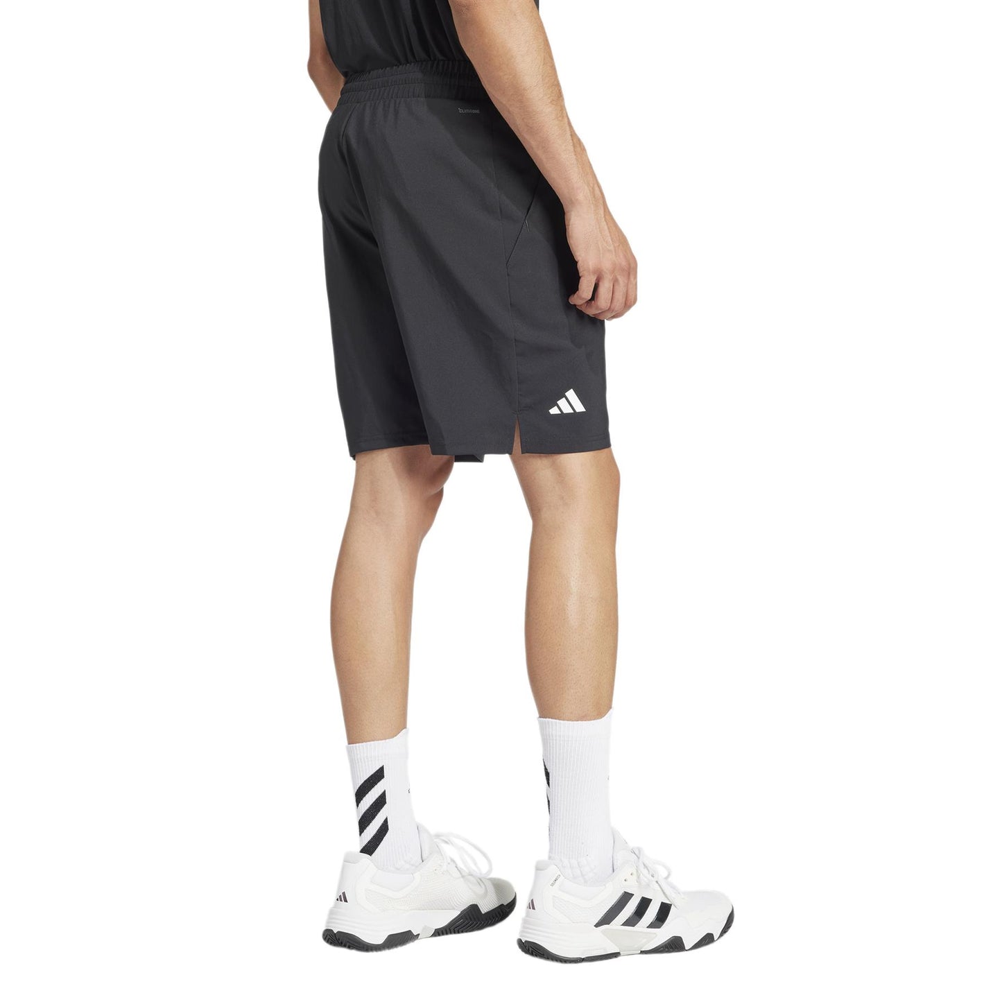 A person is seen from behind wearing black ADIDAS Men's 3 Stripe Padel Shorts and a black T-shirt, paired with white socks and three-stripe sneakers. This stylish, moisture-wicking outfit is ideal for an active day, keeping you cool on the move.