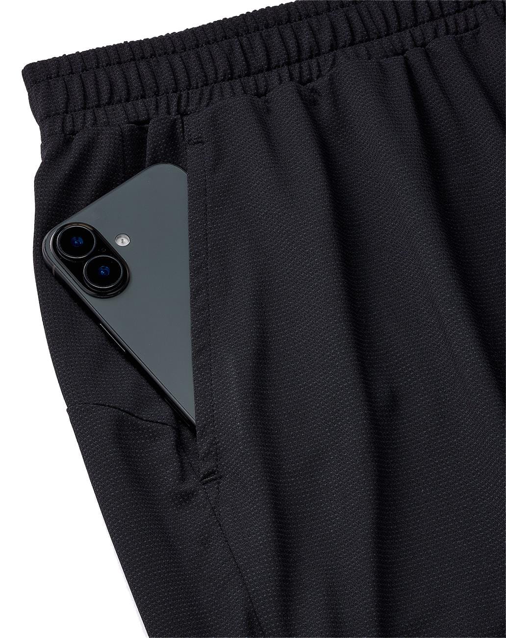 A black smartphone with dual cameras is partially tucked into the pocket of Yonex 15239YX Knit Mens Padel Shorts in black, breathable athletic shorts featuring an elastic waistband from Yonex.