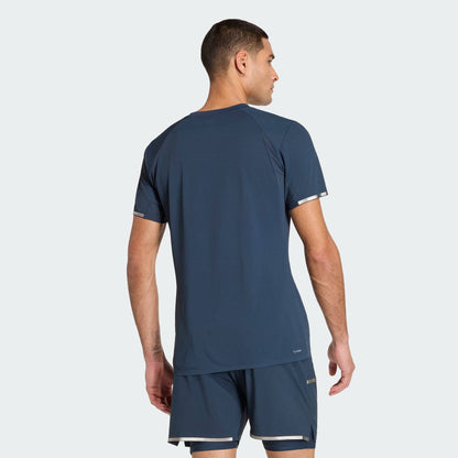 A man in an ADIDAS Climacool+ Freelift Pro Mens Padel T-Shirt - Aurora Ink and matching shorts stands with his back to the camera against a plain light background.