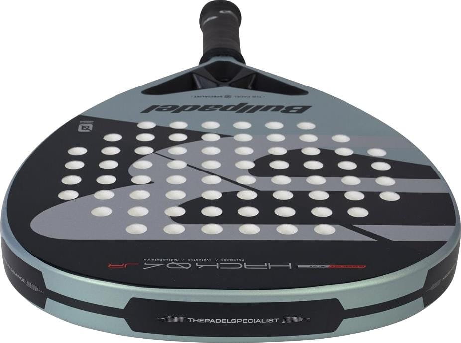 A close-up of the Bullpadel HACK Junior 2026 Padel Racket shows its black handle, grey and black face with white holes, and bold Bullpadel branding inspired by Paquito Navarro's racket on the front and edges.