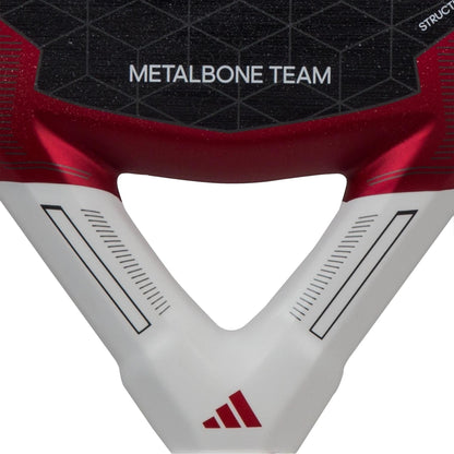 A detailed view of the handle of the ADIDAS Metalbone Team 3.3 Padel Racket - Red showcases a geometric pattern along with "METALBONE TEAM" prominently featured. The red, black, and white color scheme with sleek linear accents and a small emblem at the bottom enhances its performance-focused design, perfectly complementing its diamond-shaped head.