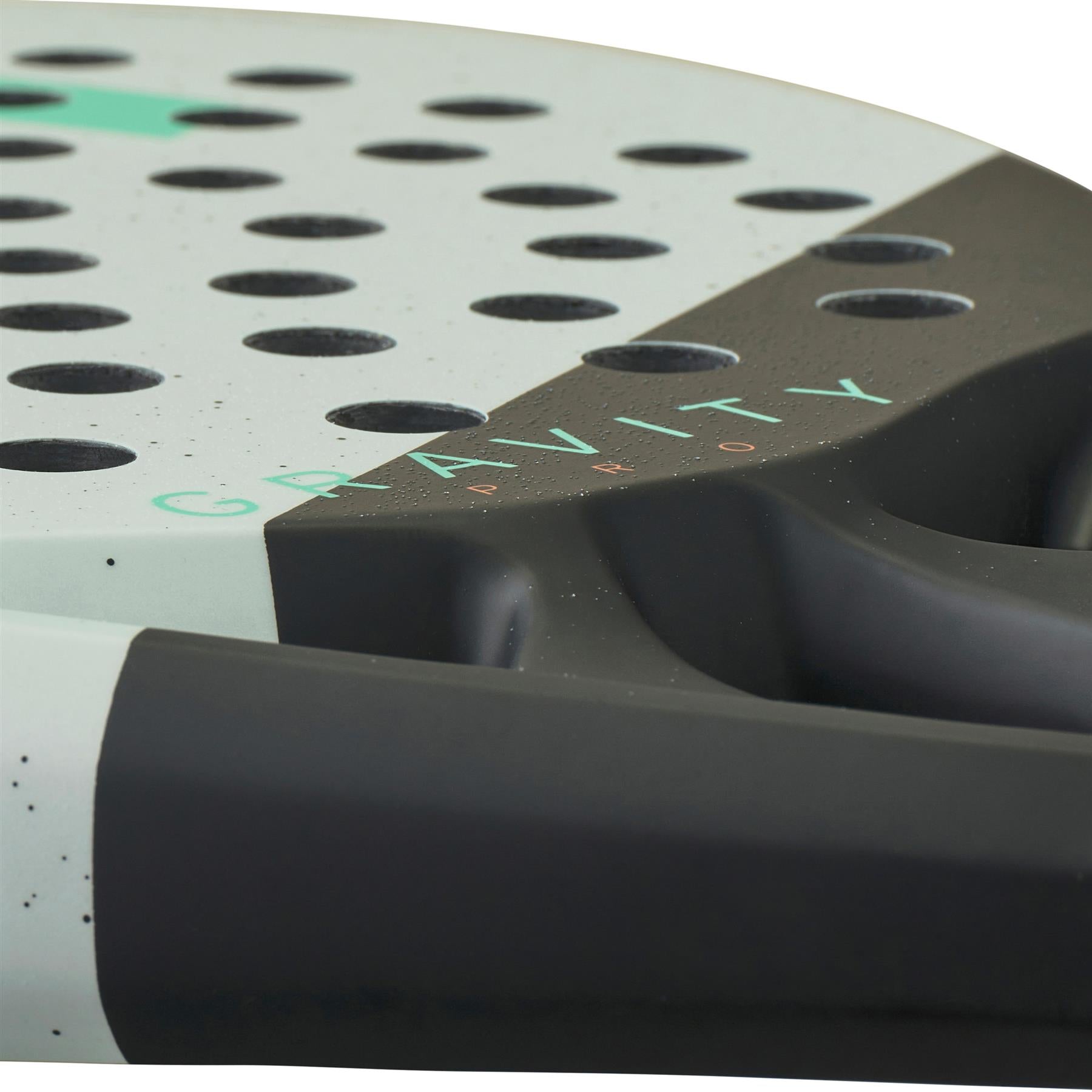 Zoomed-in view of the HEAD Gravity Pro 2024 Padel Racket in mint and black, highlighting its perforated holes and the word "GRAVITY" printed in light green on the gray surface. The black handle boasts a textured grip, leveraging Auxetic 2.0 technology for enhanced control and Spin Surface optimization.