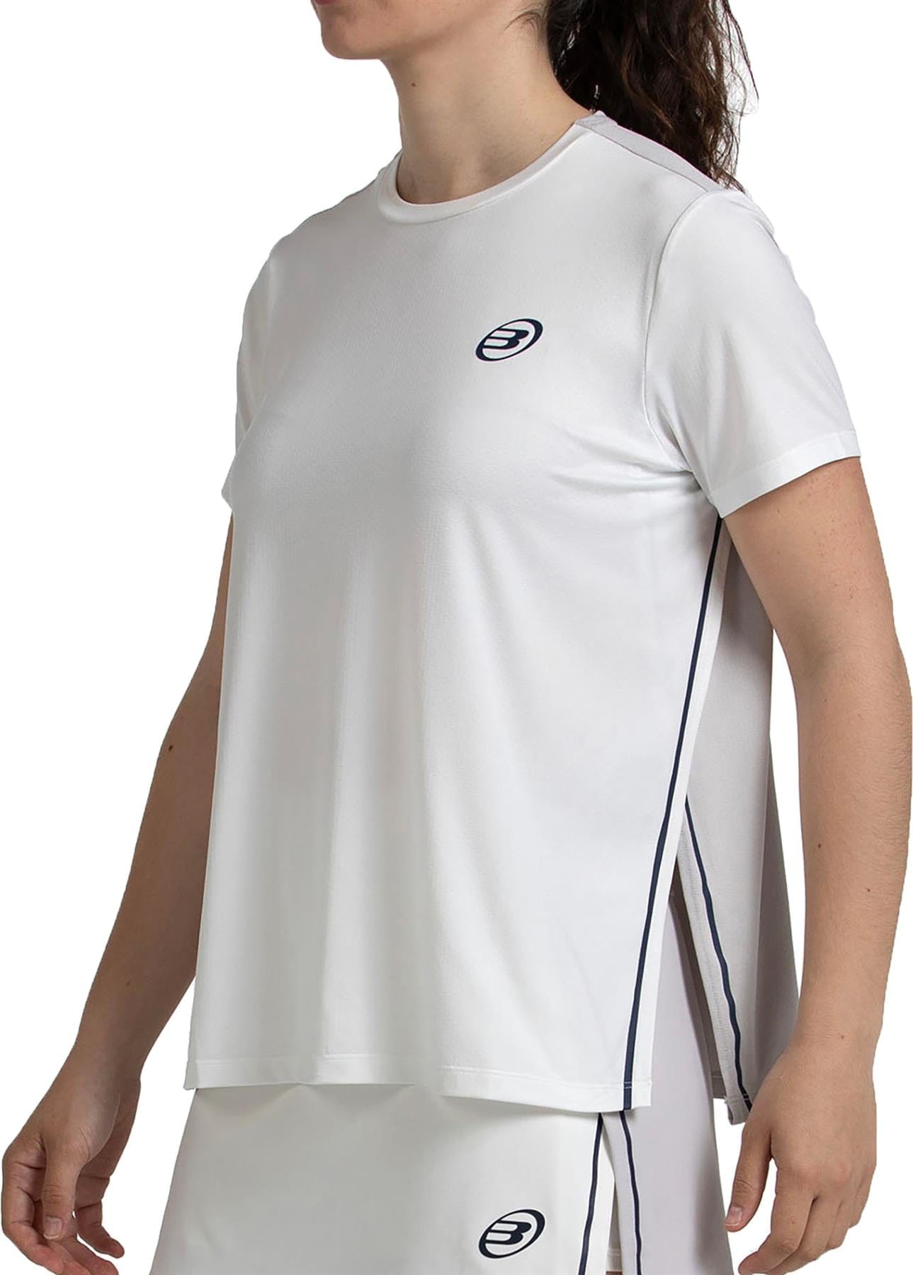 Woman in the Bullpadel Picase Women's Padel T-Shirt - Bone, a white athletic top with logo and dark piping, paired with a matching skirt—stylish padel apparel from Bullpadel with side slits and a loose fit for optimal performance.