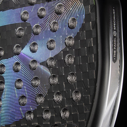 Close-up of the Bullpadel XPLO 2026 Padel Racket in black, showing carbon fiber texture, round perforations, iridescent wave patterns, "THE PADEL SPECIALIST" on the edge, and a small Bullpadel logo.