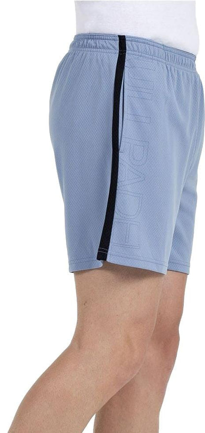 A person is shown sideways from the waist to just above the knee, wearing Bullpadel Campaza Mens Padel Shorts in Shadow Blue, featuring a black vertical side stripe and a white waistband.