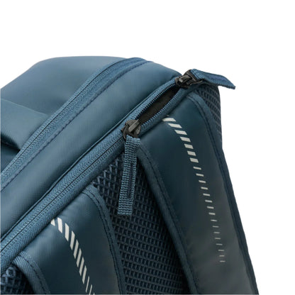 A close-up of the Kanso Intuko Padel 23L Backpack in Navy highlights a zipper with a fabric pull tab. This backpack includes a racket compartment, mesh pocket, and reflective diagonal stripes on the side for style and safety, featuring a smooth matte texture.