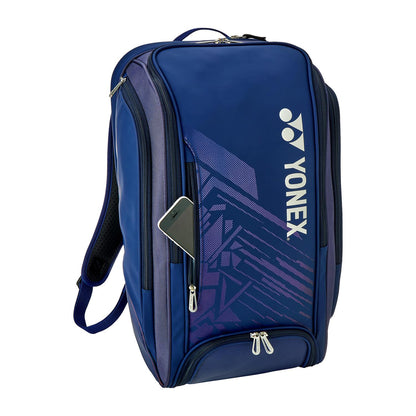 The Yonex 02512EX Expert Padel Backpack in navy blue features zippered compartments and a purple geometric design. It includes an external smartphone slot, adjustable shoulder straps, and multiple storage sections for all your sporting essentials.