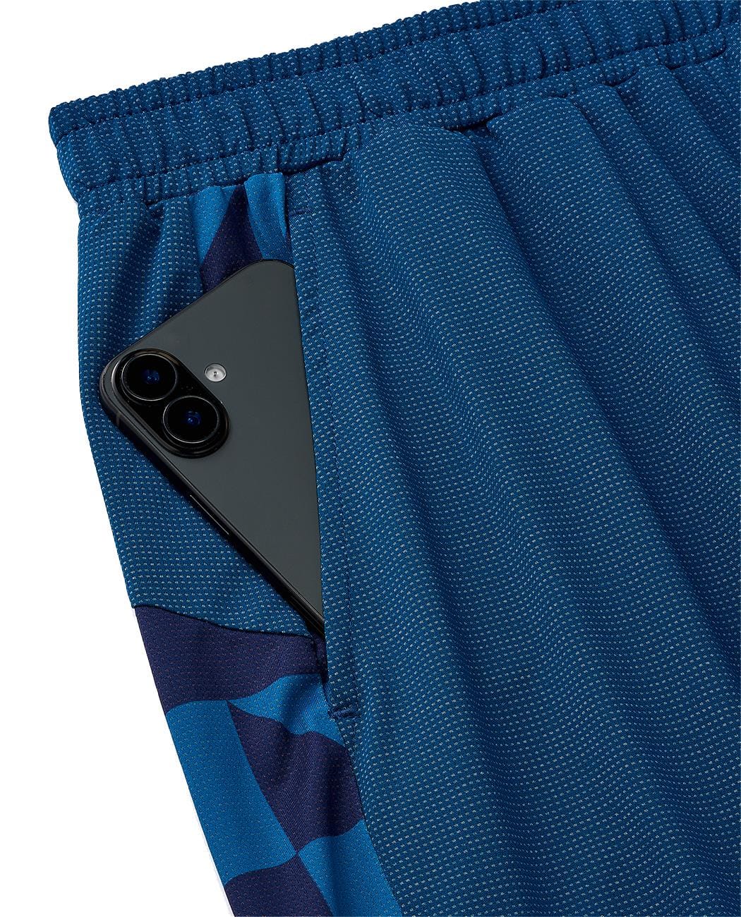 A black smartphone is partially visible in the front pocket of Yonex 15240YX Knit Men's Padel Shorts—Indigo Blue men’s athletic shorts by Yonex featuring a dark blue geometric pattern and breathable knit fabric.