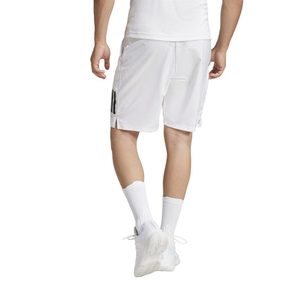 A person in ADIDAS Men's 3 Stripe Padel Shorts - White, complete with a white shirt, white sneakers, socks, and the black-striped shorts is walking away against a plain white background.