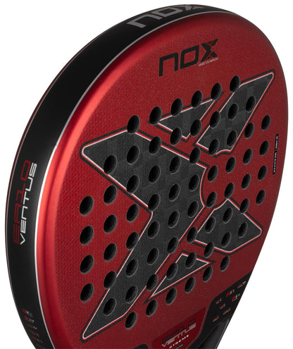 Close-up of the NOX Luxury EA10 Ventus Hybrid 12K XTREM By Edu Alonso 2026 padel racket, showing its red and black carbon 12K build, textured surface, round shape, perforated holes, and prominent NOX branding.