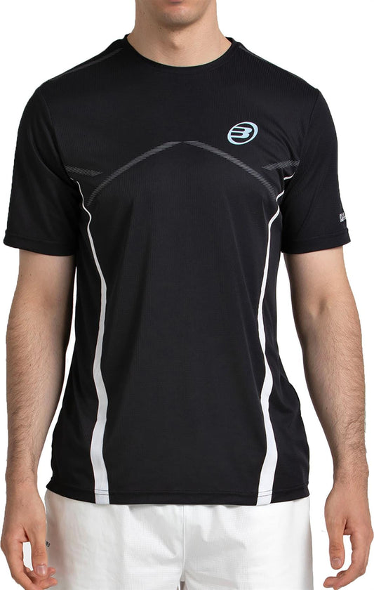 A man in a Bullpadel Cabore Men's Padel T-Shirt - Black from Bullpadel, featuring quick-drying fabric, white accents, and a small blue logo, pairs it with white shorts while standing against a plain background.