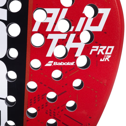 Close-up of the Babolat Alioth Pro Junior Padel Racket in red and black, featuring white “ALD TH PRO JR” text, circular holes, geometric patterns on the surface, and a central Babolat logo.
